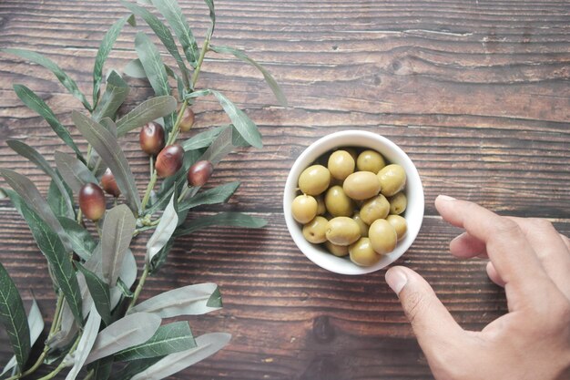 Recoger a mano aceitunas frescas en un recipiente sobre la mesa