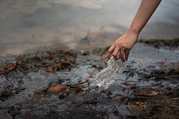 Recoger a mano botella de plástico del agua.