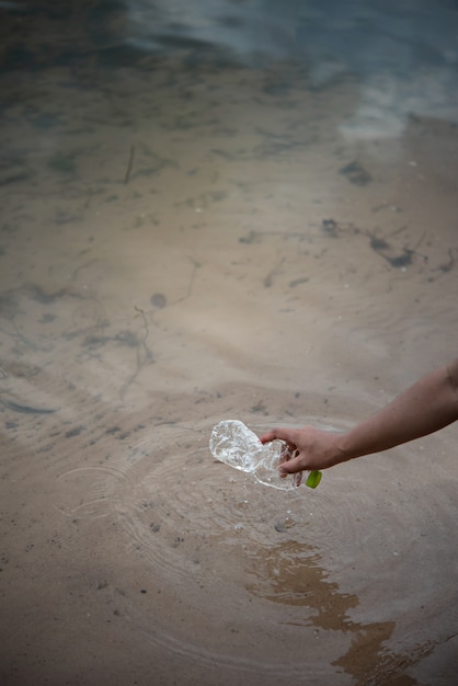 Recoger a mano botella de plástico del agua.