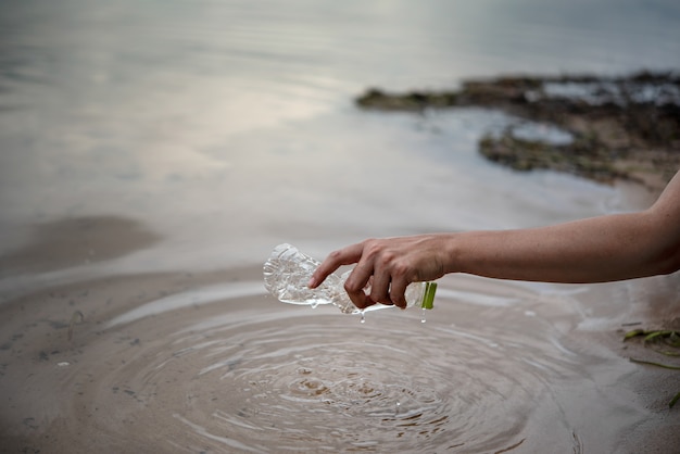 Recoger a mano botella de plástico del agua.