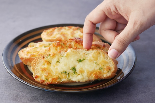 Recoger a mano un pan de ajo en un plato