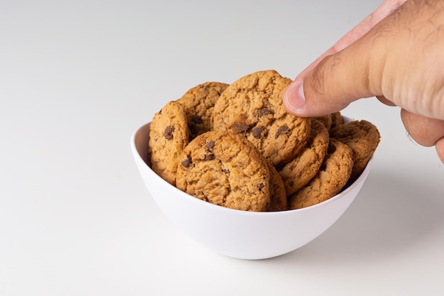 Recogiendo galletas de tazón blanco sobre fondo blanco aislado