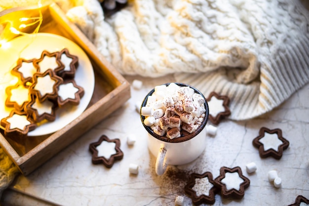 Reconfortante taza de comida navideña de chocolate caliente con malvavisco y galletas con luces acogedoras