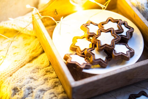 Reconfortante taza de comida navideña de chocolate caliente con malvavisco y galletas con luces acogedoras