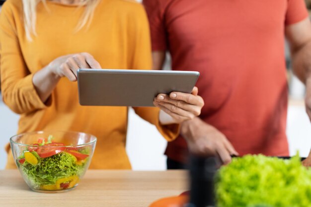 Recortada de hombre y mujer usando una almohadilla digital mientras cocina