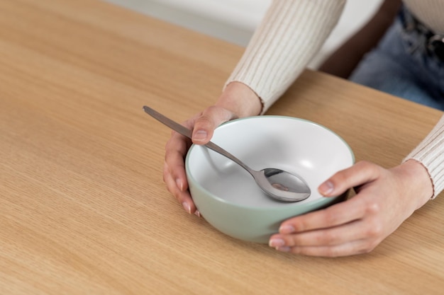 Recortada de mujer sosteniendo un plato vacío con una cuchara dentro