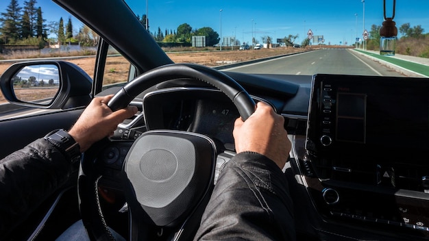 Recortado de homem dirigindo carro por cima do ombro, motorista caucasiano irreconhecível, segurando as mãos no volante, dirigindo um novo automóvel agradável