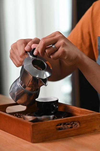 Recortado tiro joven haciendo café de la mañana con moka pot