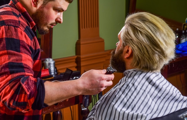 Recortar la barba Rutina de belleza Mantener la forma El hombre se sienta en la silla de peluquero Peluquería Cliente de la barbería Servicios de barbería Excelente peluquero que no apura el corte de pelo Visita al peluquero