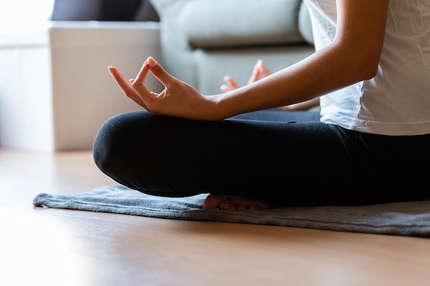 Recortar mujer joven irreconocible haciendo yoga en casa