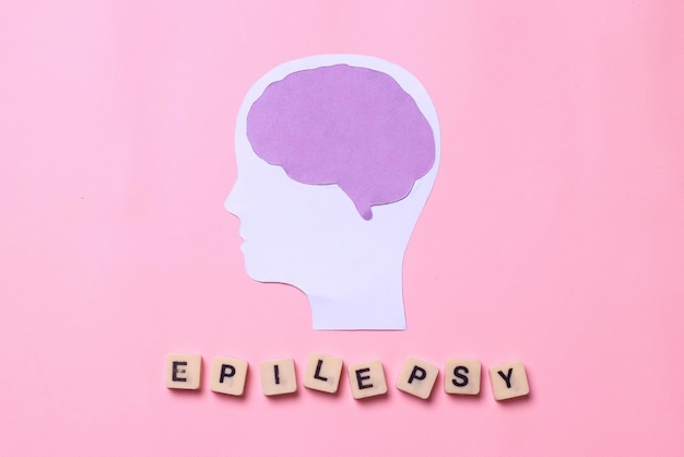 Recorte de papel cerebral com letras de epilepsia em cubos isolados em fundo rosa