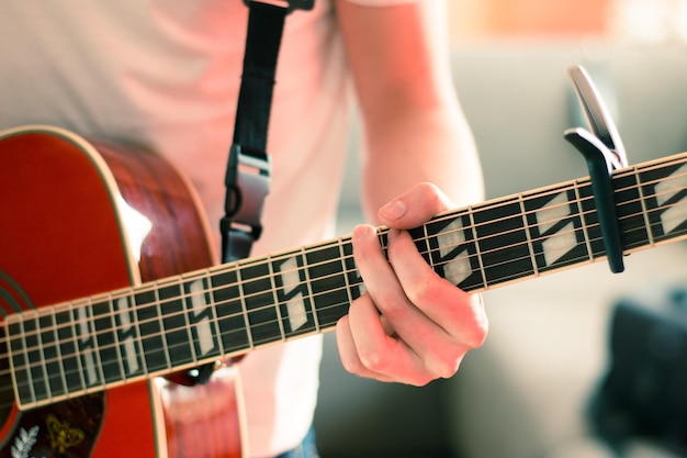 Recorte de um jovem tocando uma guitarra ocidental sunburst