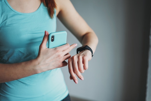 Foto recorte la foto de la ropa deportiva azul claro en forma de mujer joven haciendo entrenamiento con un reloj móvil y de fitness en el estudio de la clase de entrenamiento