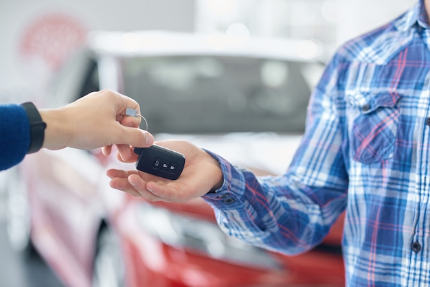 Recorte de manos cuando una persona le da la llave del automóvil a otra.