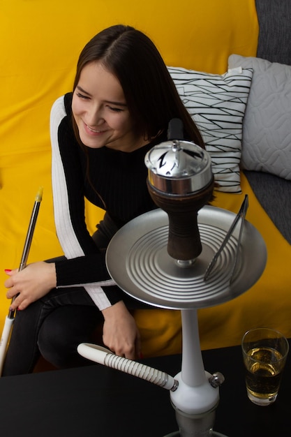 Recreação e entretenimento. Linda menina fuma narguilé em um bar, se divertindo com os amigos, sorrindo, bebendo