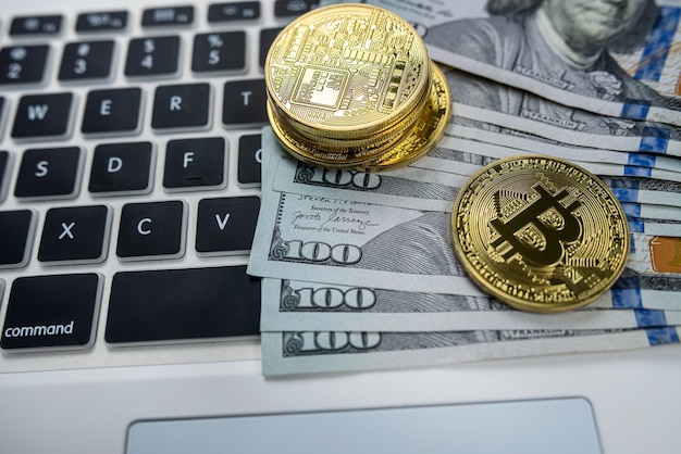 Recuerdo dorado bitcoin con billetes de dólar en el teclado del portátil aislado sobre fondo negro