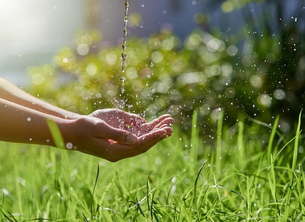 El recurso más preciado de la naturaleza tiro de manos extendidas para atrapar un chorro de agua afuera