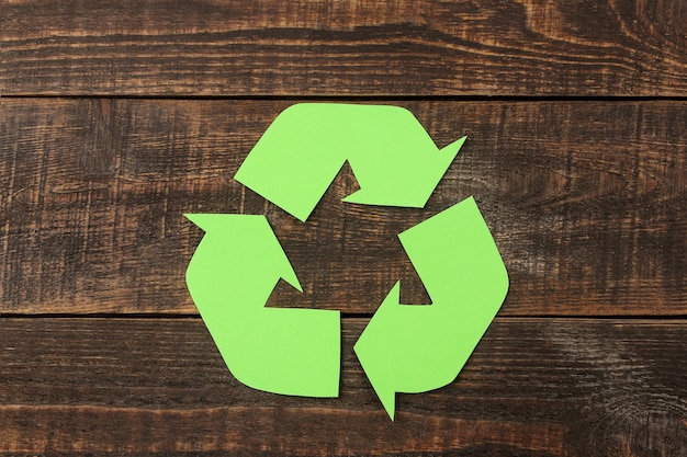 Recycling-Schild auf einem braunen Holztisch. von oben betrachten. Öko-Konzept