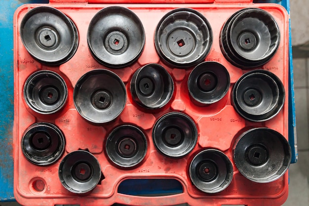 Foto red box con un juego de tapas extraíbles para filtros de aceite de diferentes tamaños y diámetros para la extracción segura de piezas viejas en un taller de reparación de vehículos industria de servicios de automóviles