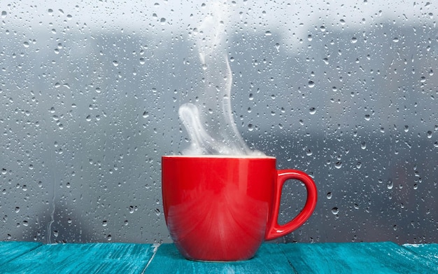 Foto red cup with steam coming out of it on a rainy day