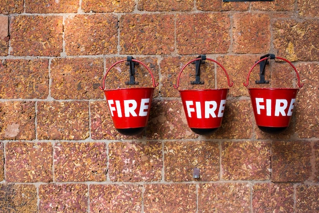 Red fire bin contiene la arena en el fondo de la pared de ladrillo