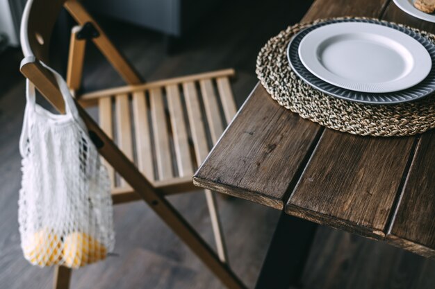 Una red con fruta fresca cuelga de una silla de madera en la cocina. Detalles del interior de la cocina