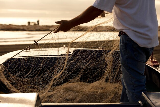 Red de pesca de pesca en manos de pescadores. En la playa, mar a fondo