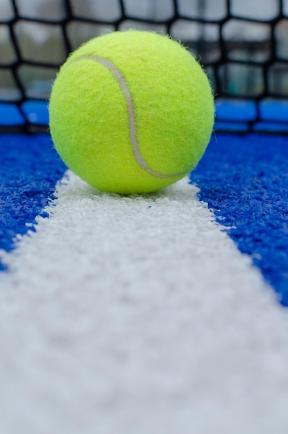 Foto red de una pista de pádel azul y una pelota en la línea blanca