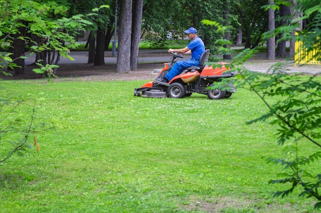 Foto red rideon rasenmäher auf grünem rasen mit fahrendem mann im freien im park mit technologie