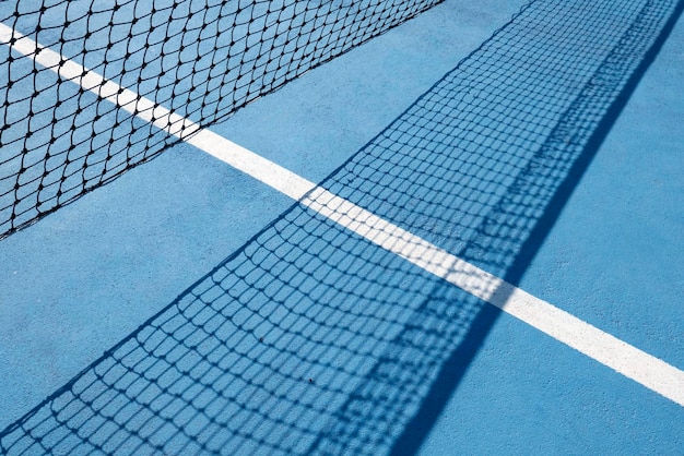 Red de tenis en azul. Parte de una red de tenis y su sombra. Composición dinámica