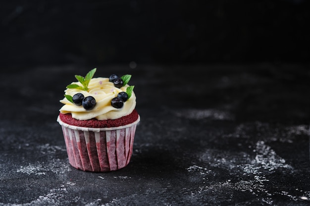 Red Velvet Cupcakes mit Frischkäsecreme. Dessert garniert mit frischen Blaubeeren und Minze.