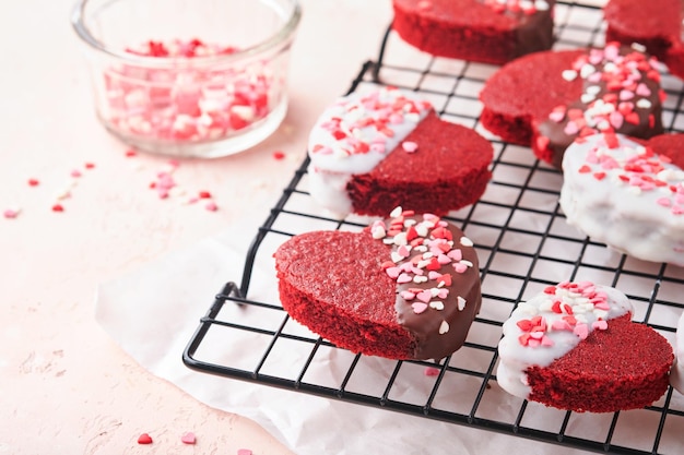 Red Velvet oder Brownie Cookies auf Herz geformt in Schokoladenglasur auf einem rosa romantischen Hintergrund Dessert-Idee für den Valentinstag Mutter- oder Frauentag Leckeres hausgemachtes Dessert Kuchen zum Valentinstag