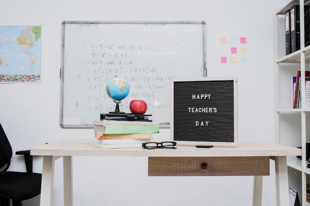 Redacte el día de los maestros felices dispuestos en la pantalla del tablero de letras en la mesa del salón de clases.