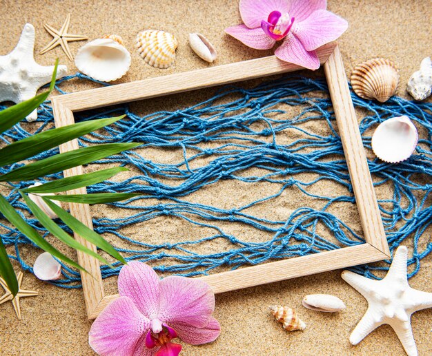 Foto rede de pesca e moldura de madeira na areia da praia