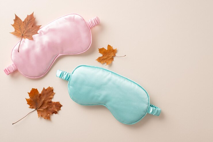 Redefine a sua experiência de sono com os nossos itens essenciais escolhidos a dedo Visão de cima para baixo retratando máscaras de sono cor-de-rosa e azul posicionadas sobre um fundo bege calmante com espaço para publicidade ou elementos textuais