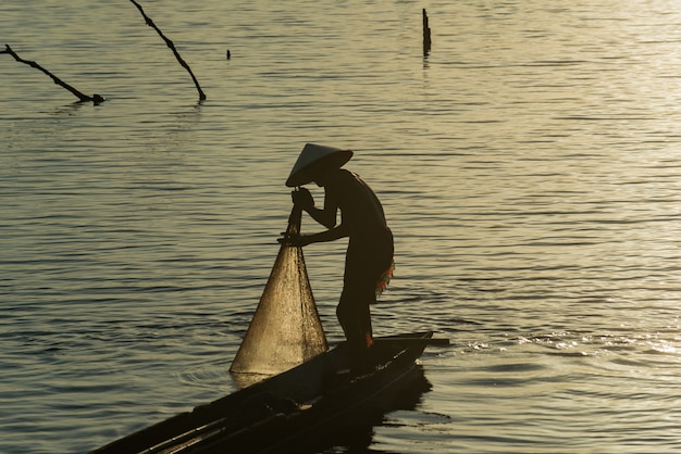 Redes de pesca do pescador da silhueta no barco.