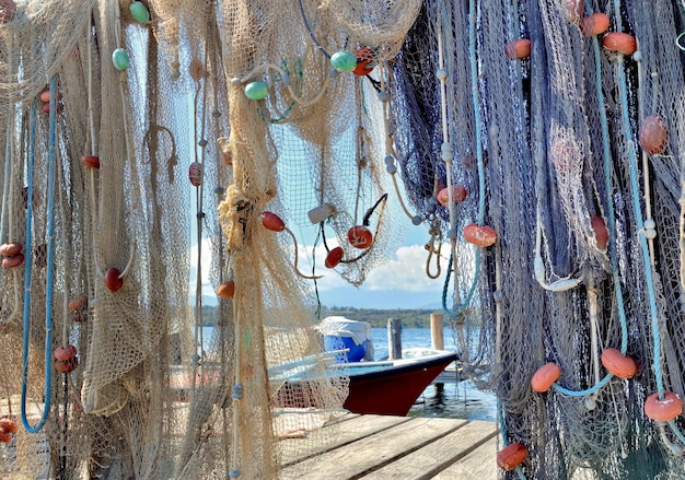 Redes de pesca penduradas num pontão em frente a um barco