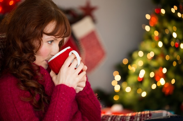 Redhead bonito que bebe a bebida quente no Natal
