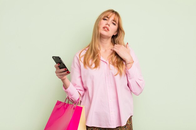 Redhead hübsche Frau mit Einkaufstüten und einem Smartphone