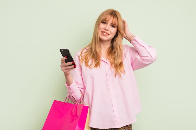 Redhead hübsche Frau mit Einkaufstüten und einem Smartphone