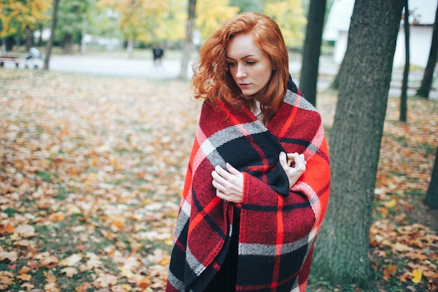 Redhead Mädchen auf rotem Plaid im Herbst Park