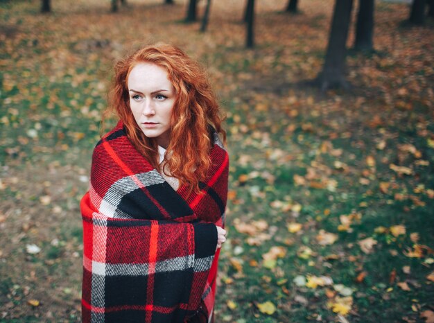 Redhead Mädchen auf rotem Plaid im Herbst Park