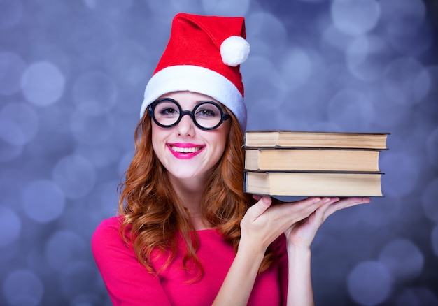 Redheadmädchen im Weihnachtshut mit Büchern