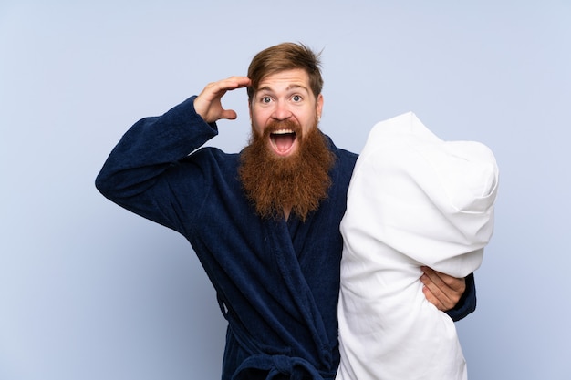 Redheadmann in den Pyjamas über getrennter Wand mit Überraschung und entsetztem Gesichtsausdruck