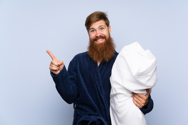 Foto redheadmann in den pyjamas zeigend auf die seite, um ein produkt darzustellen