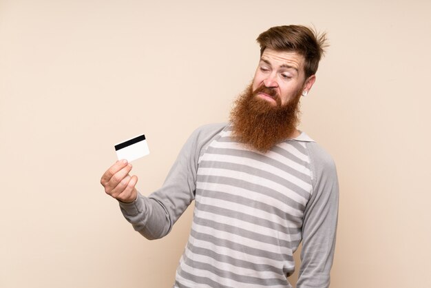 Redheadmann mit dem langen Bart, der eine Kreditkarte anhält