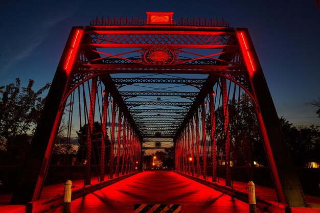 RedLit Truss Bridge no Crepúsculo com fundo urbano