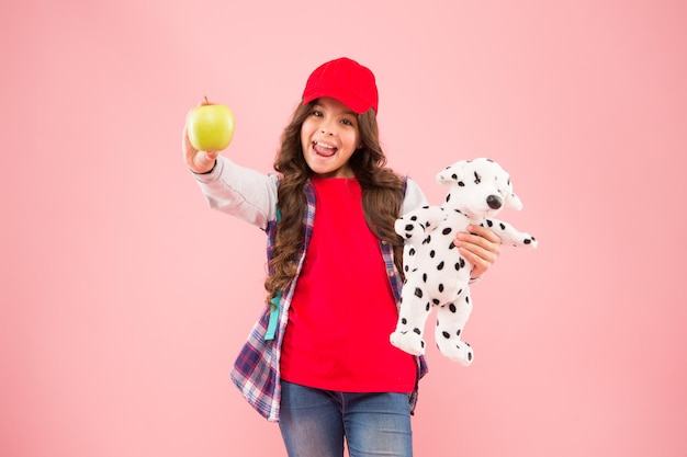 Reducir el estrés Niña pequeña colegiala de moda con mochila llevar perro de peluche y sostener manzana Estilo de vida saludable Bienestar mental y físico Colegiala vida diaria Colegiala elegante