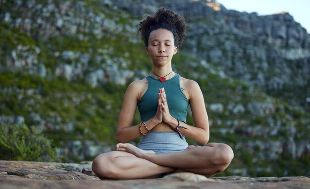 Reduzca la velocidad y deje que la meditación lo lleve en un viaje Fotografía de una mujer joven que medita mientras está en las montañas