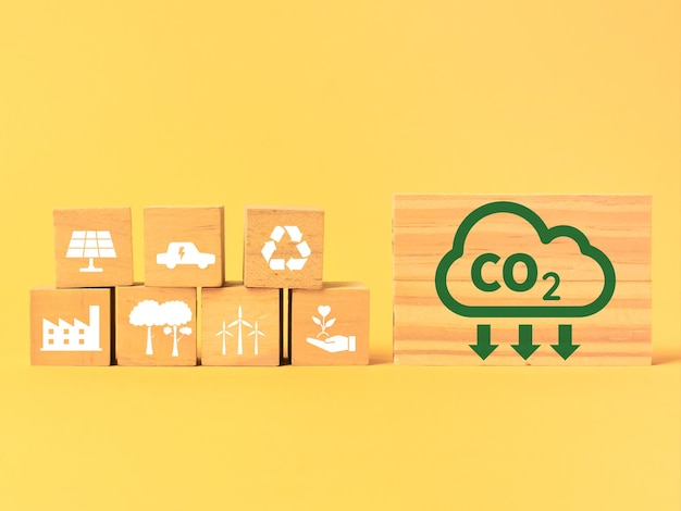 Reduzierung des CO2-Fußabdrucks mit Symbolen auf Holzklötzen.